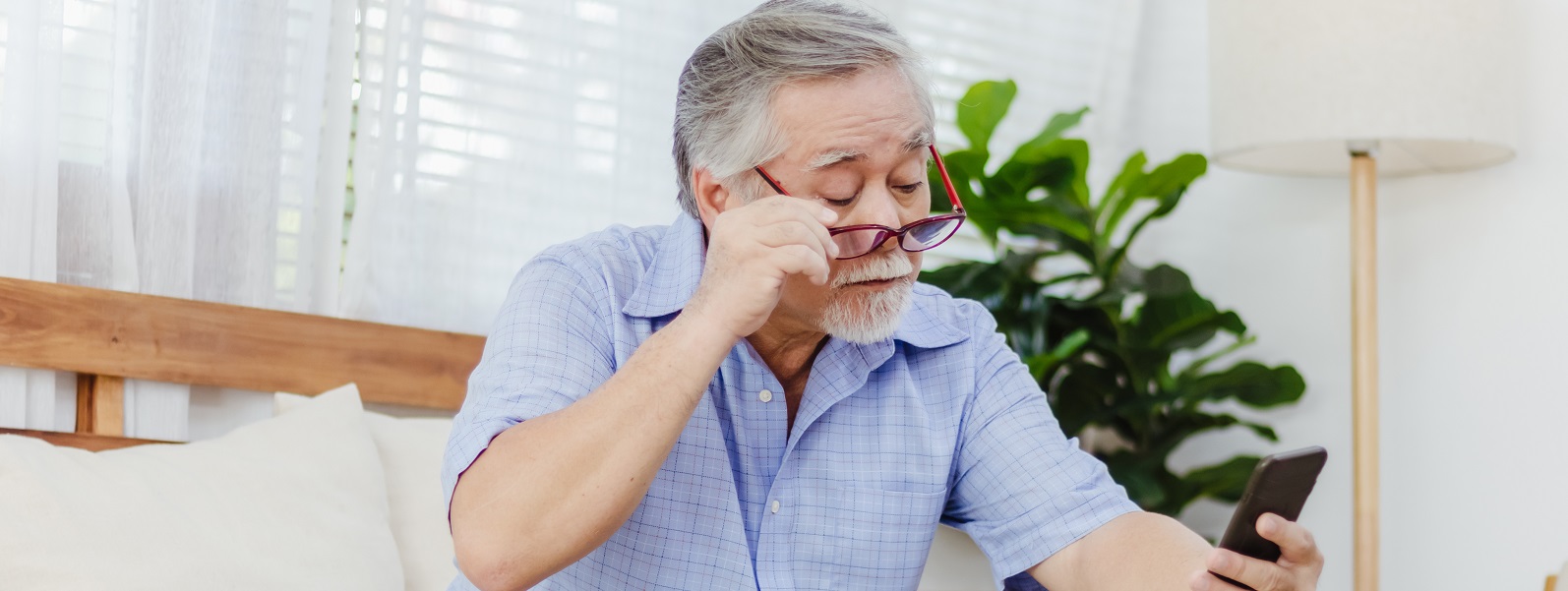 Elderly man struggling to read from smartphone