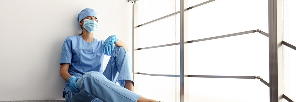 Tired overwhelmed nurse sitting on floor in hospital
