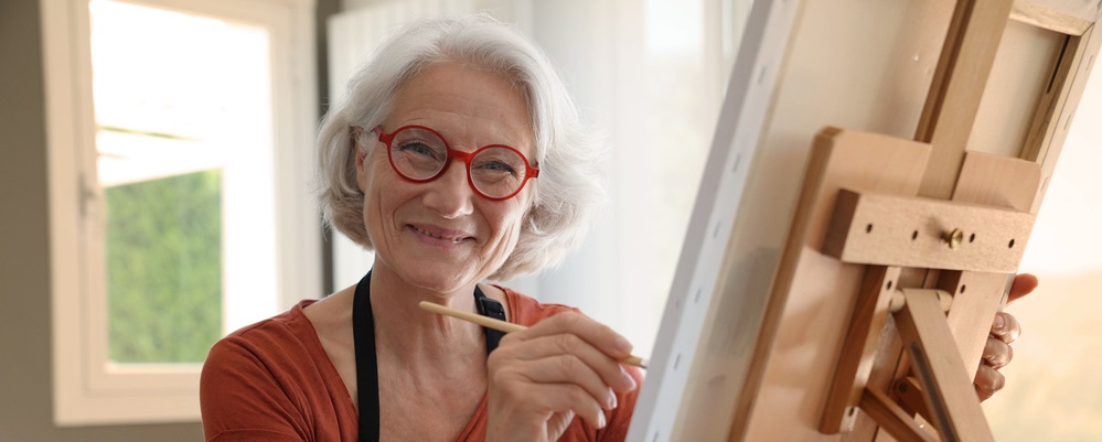 Happy Senior woman painting on canvas